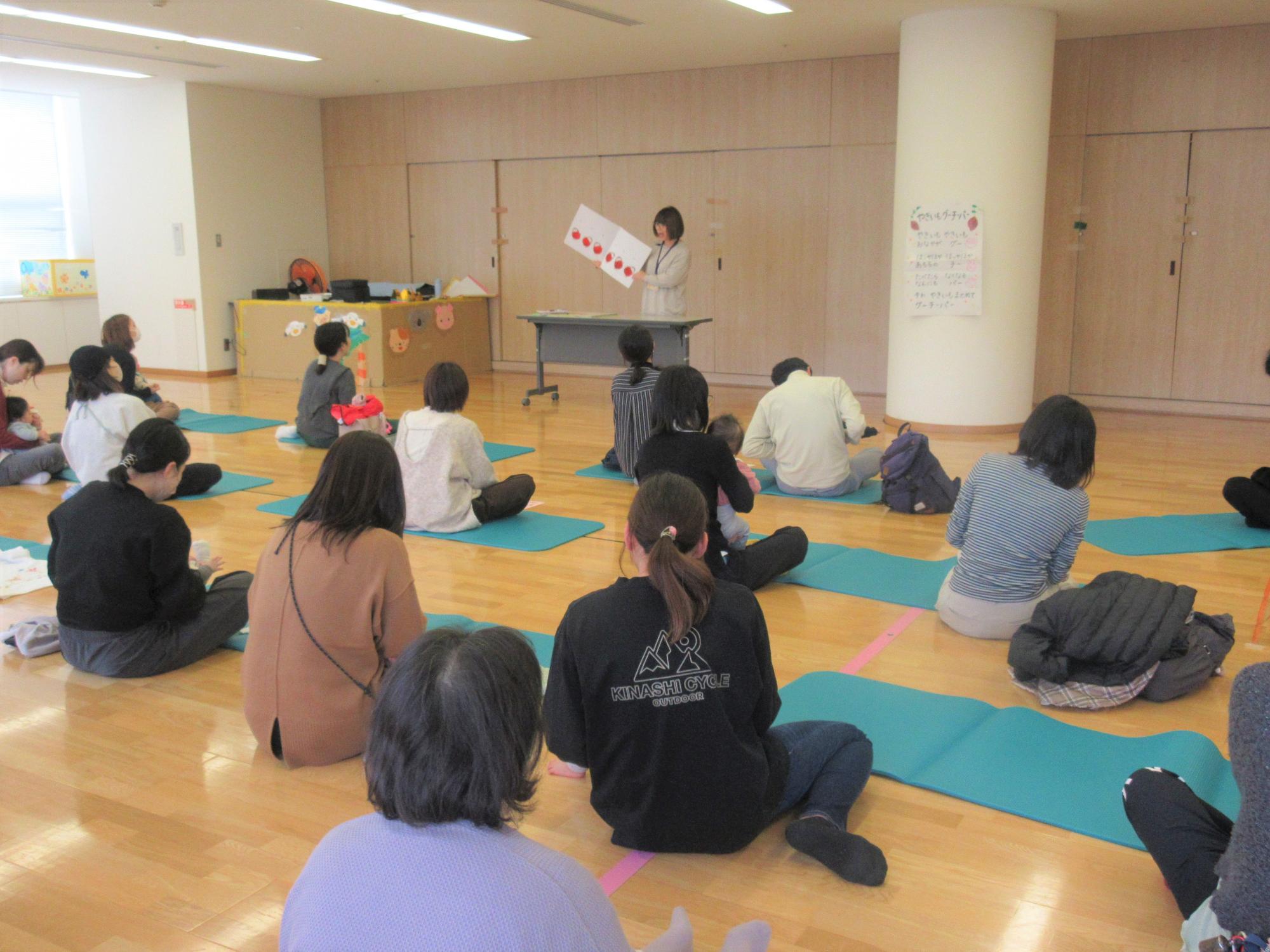 「だるまさんが」の大型絵本の読み聞かせに合わせて、親子でふれ合っている様子