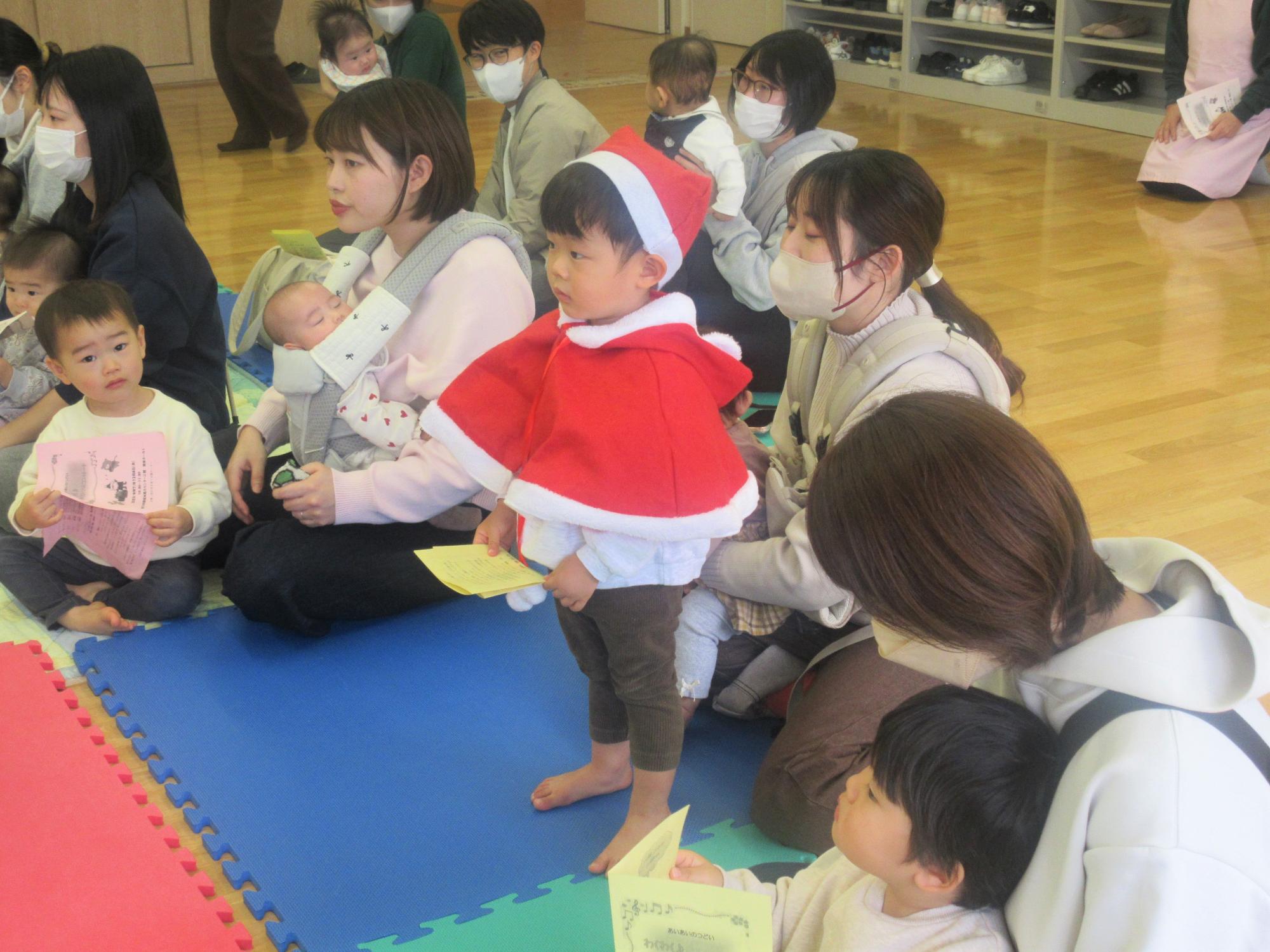 サンタさんの格好をしたかわいいこどもが拍手しながら演奏を楽しんでいる様子