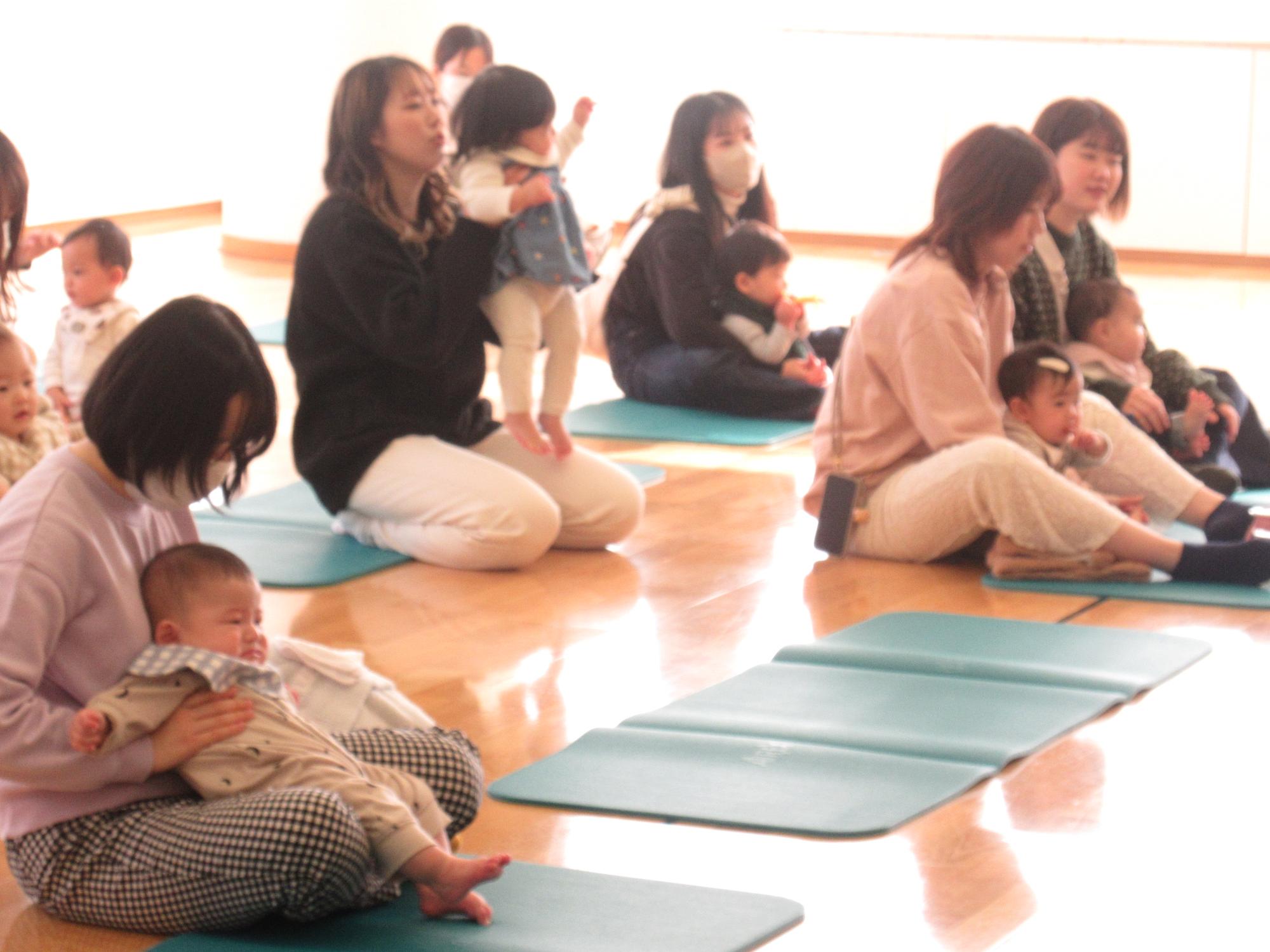 童謡「ゆきだるまのチャチャチャ」の歌に合わせて、親子で身体を揺らしたり手をたたいて楽しんでいる様子