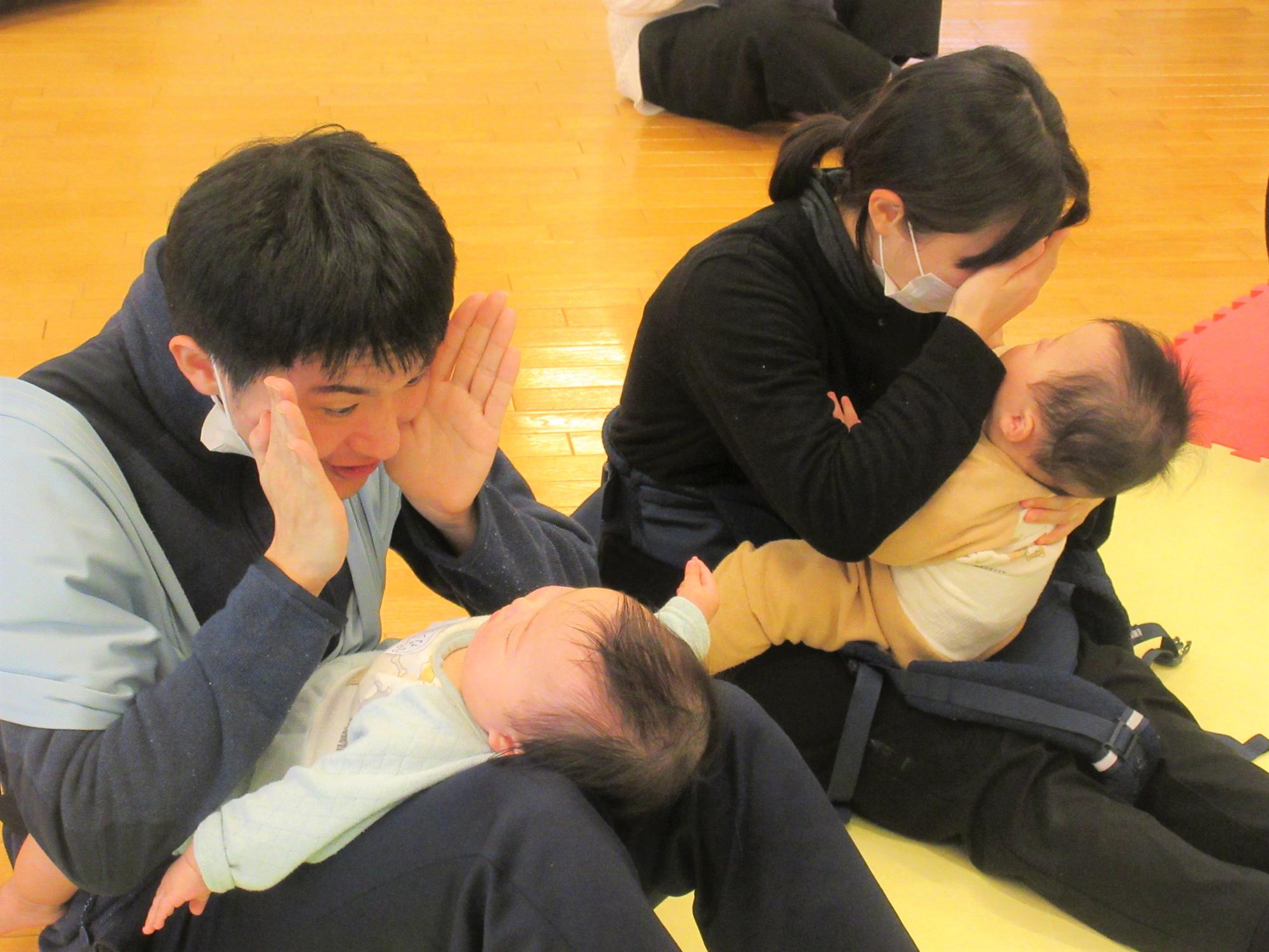 お父さんお母さんと向き合って、いないいないばあ！をしてもらいたのしんでいる姿。