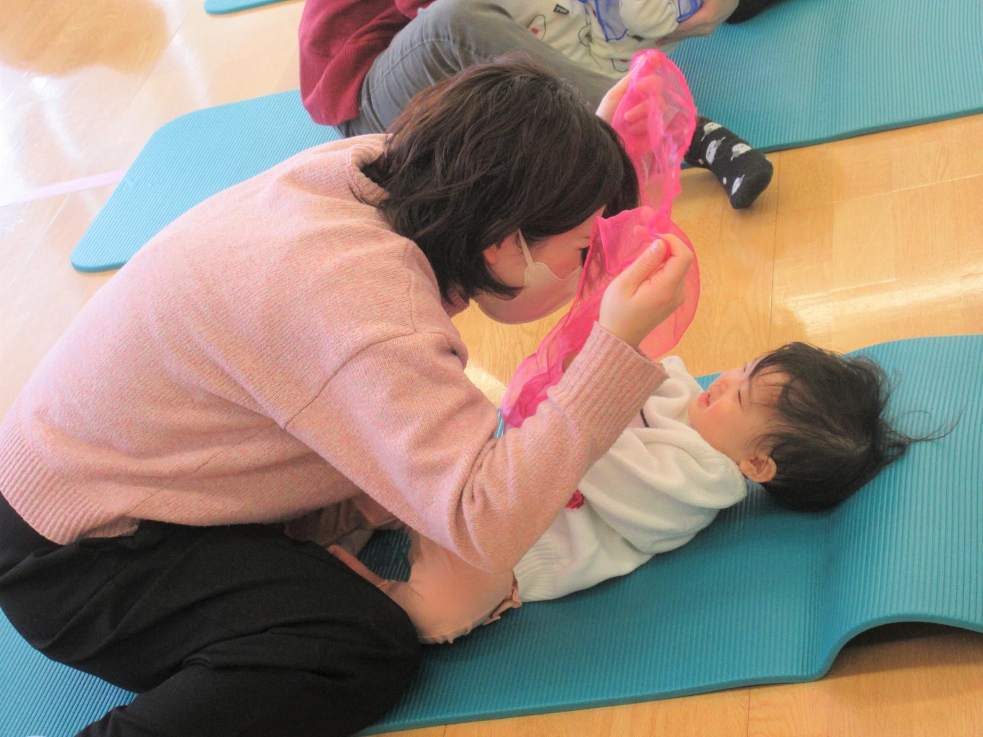 色鮮やかなオーガンジーを使って、親子でいないいないばあを楽しんでいる様子