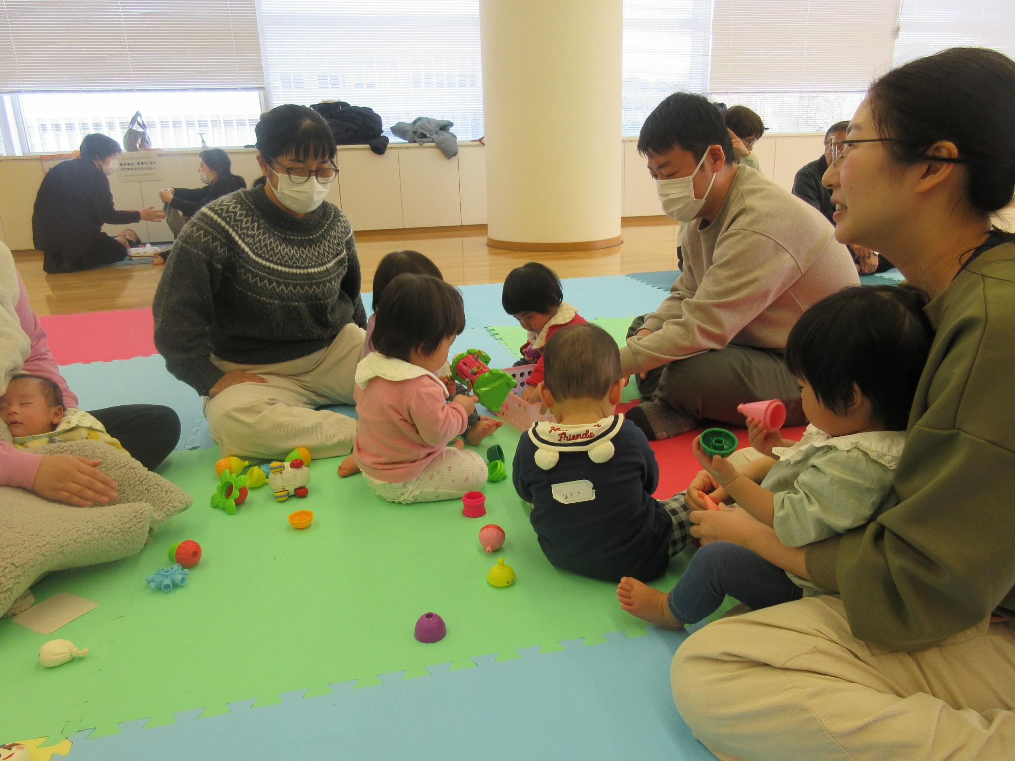 お母さんお父さんたちが、こどもを遊ばせながらおしゃべりを楽しんでいる様子