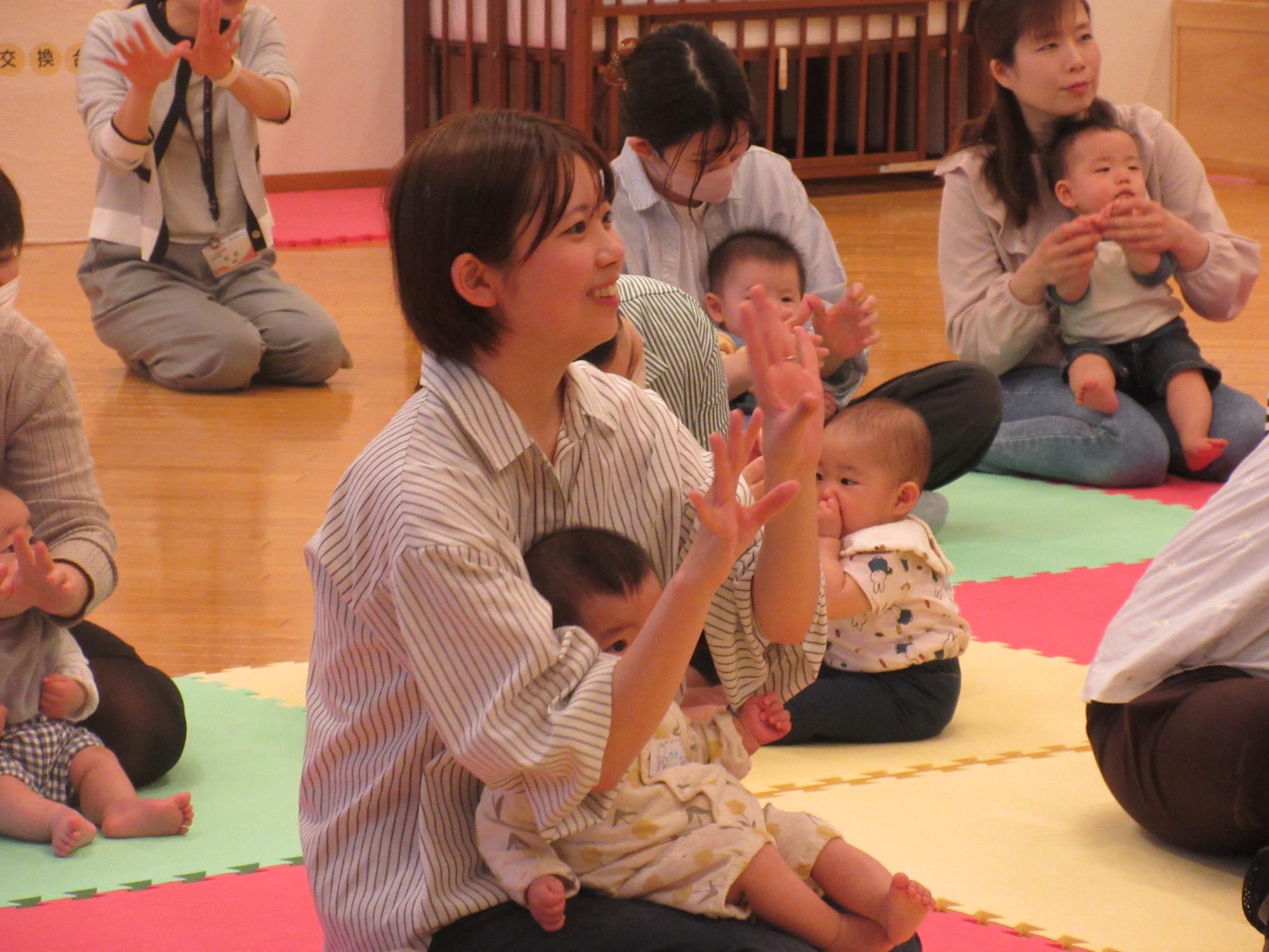 お母さんの膝の上で、てあそびを楽しんでいる様子