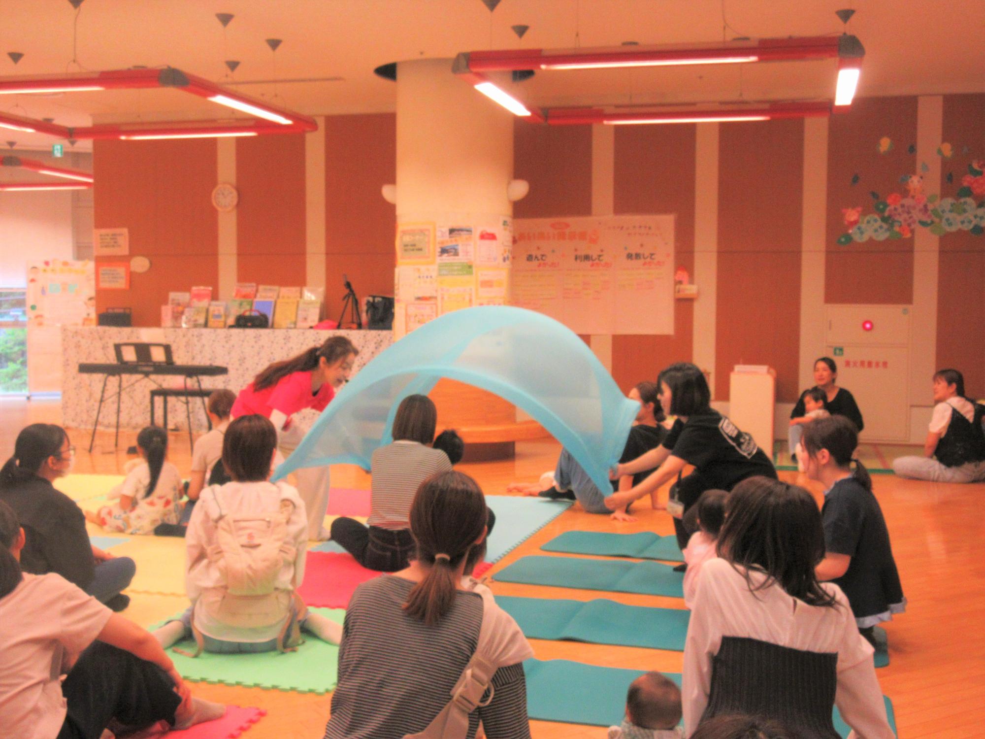 大きな布をふわふわさせながら親子を包み込んでいる様子
