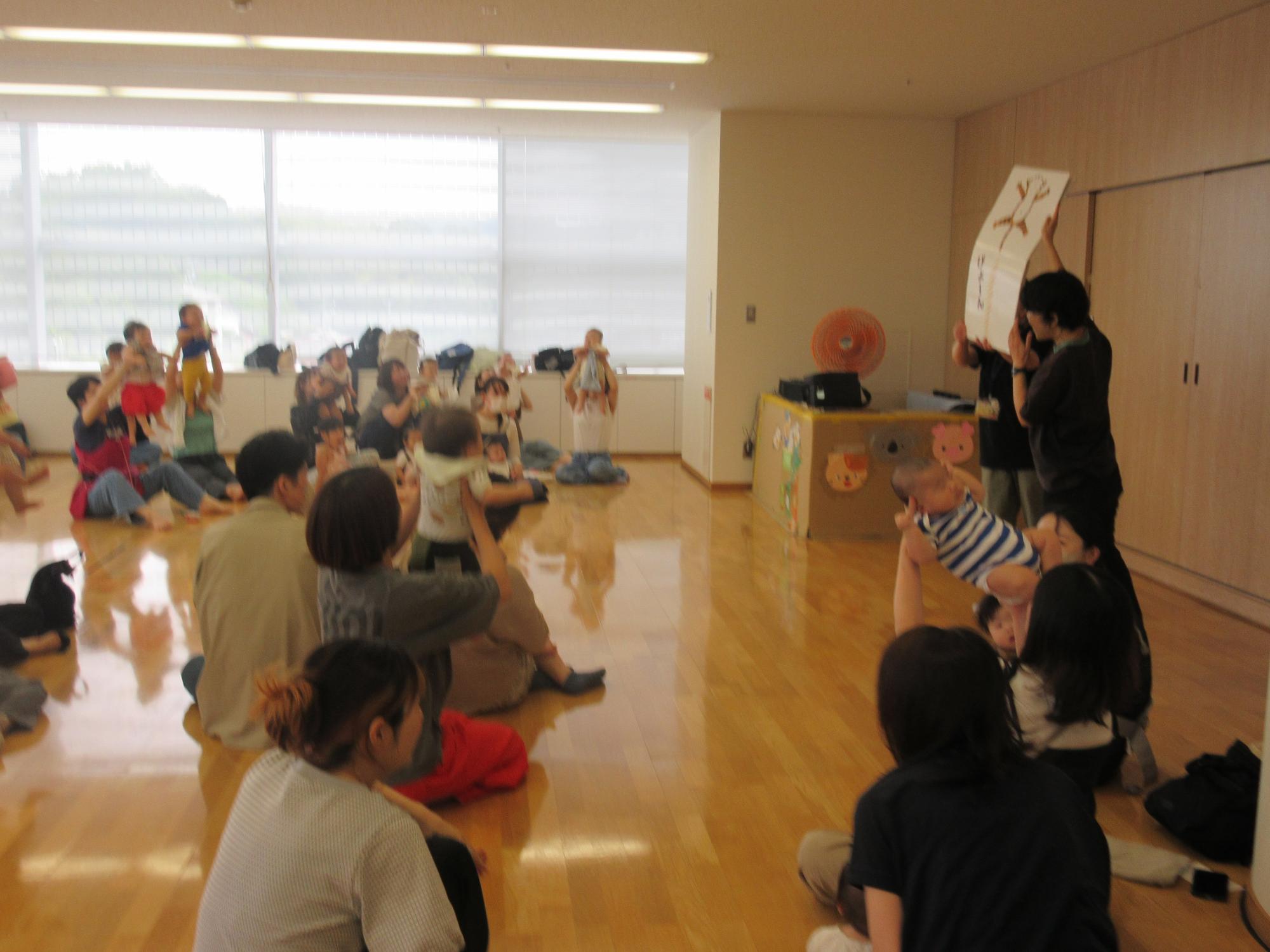 あいあいぼっくすで大型絵本に合わせて高い高いをしてもらう喜んでいる様子