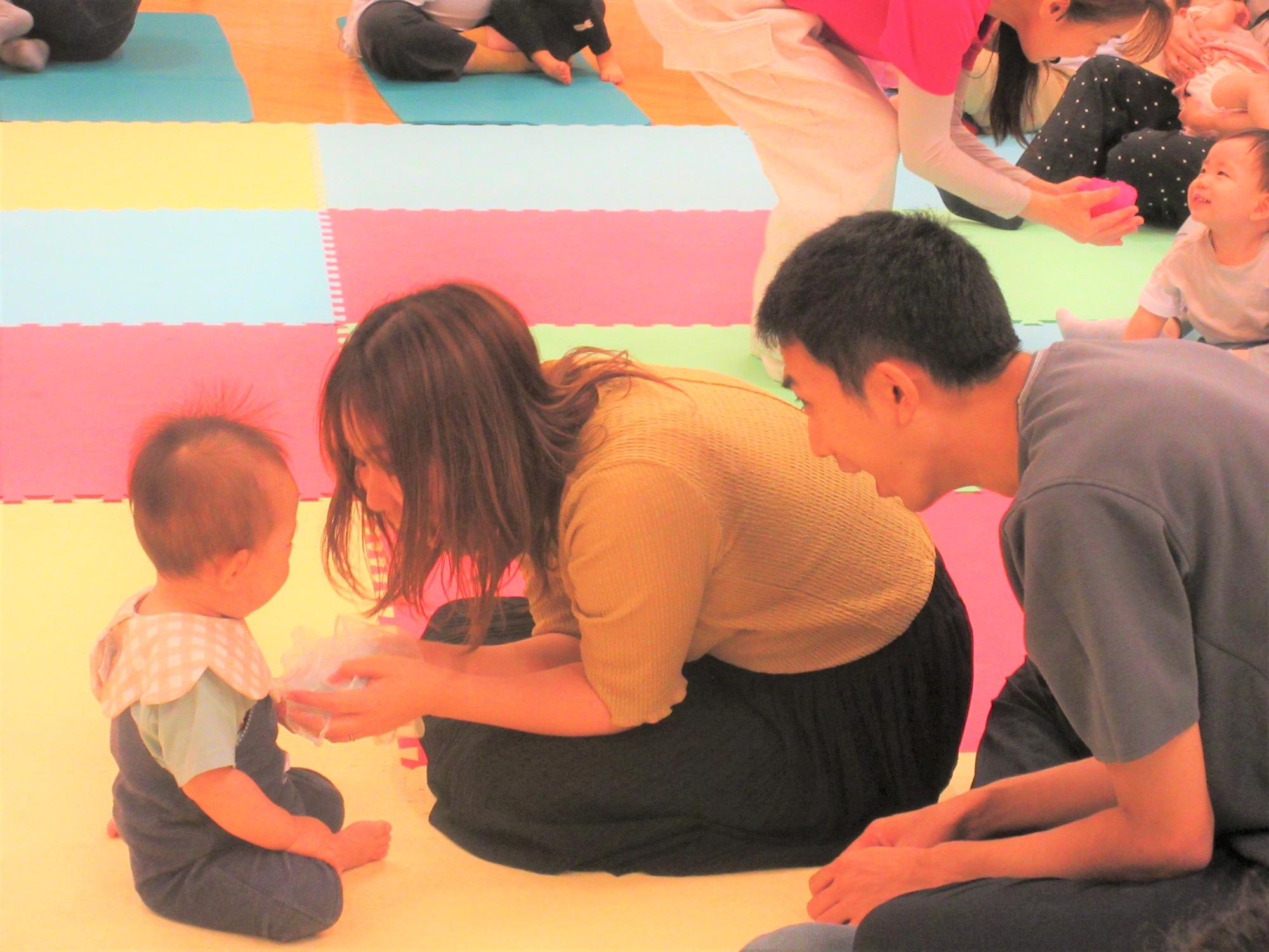 布を使ってひらひらさせたり、あいないいないばあ！したりして、親子で遊んでいる様子
