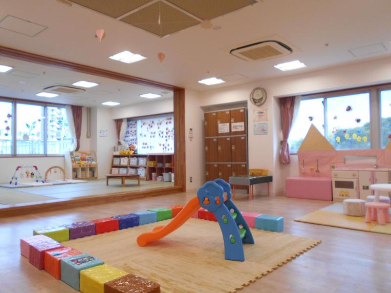 プレイマットが敷かれすべり台がある育児サロンのあそび場の写真