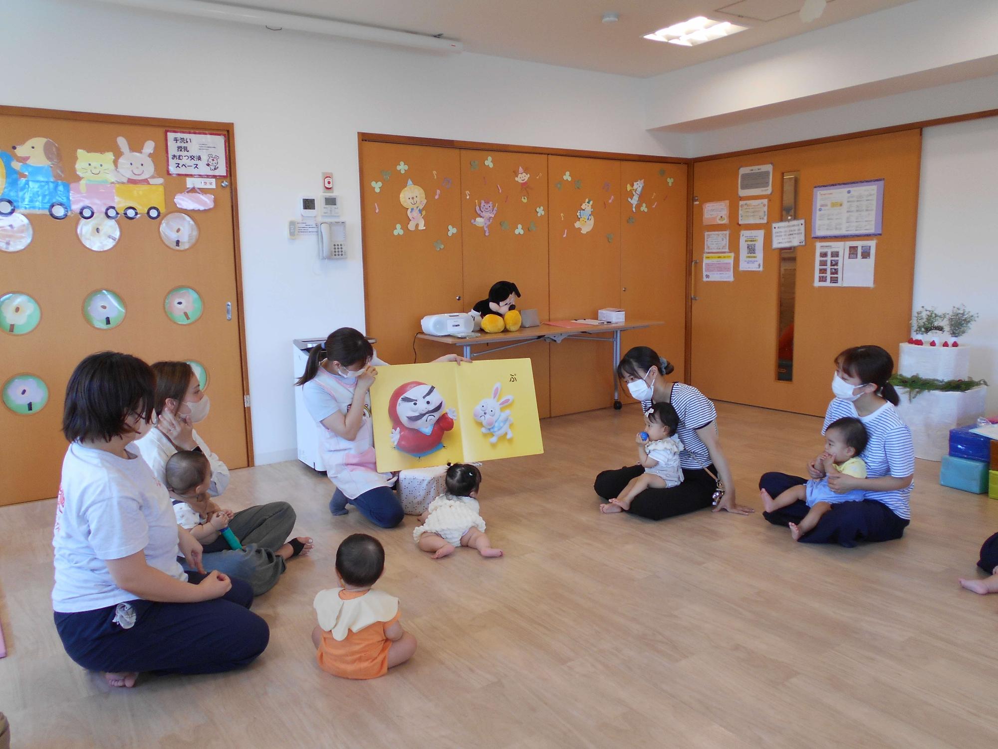 つどいで、親子で大型絵本の読み聞かせに合わせて、ふれ合っている様子