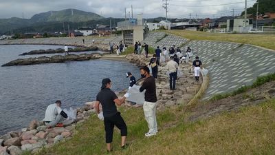 水辺付近でゴミ拾いをしている人たちの写真