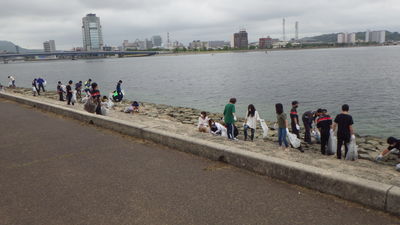 川のそばでゴミ拾いをしている人たちの写真