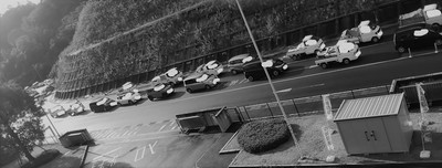 カーブ差し掛かる片側二車線の山道で、対向車線が渋滞している様子を撮影したモノクロ写真
