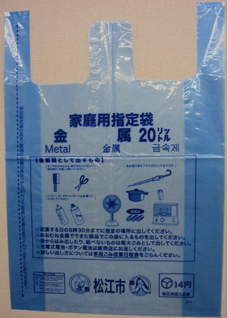紙や布に包んだ刃物類を入れる為の指定ごみ袋。青色で家庭用指定袋金属20リットルと書かれている。