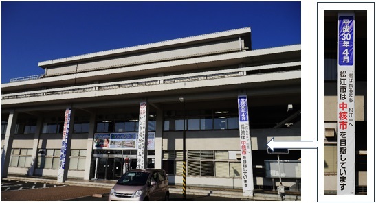 市役所正面玄関前に掲げた懸垂幕と「選ばれるまち松江へ。平成30年4月。松江市は中核市を目指しています。」と書かれた懸垂幕のアップ写真