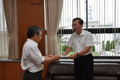 ワイシャツ姿の松浦松江市長が溝口島根県知事に依頼文書を手渡す様子の写真