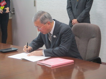 引継書に署名するスーツを着た松浦市長の写真