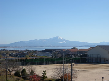 山頂に雪が積もっている大山と眼下にある運動場の写真