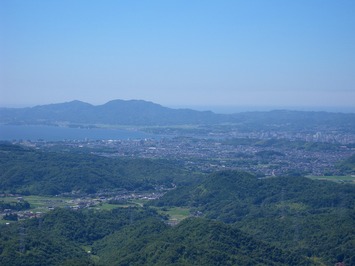 薄い雲があるぼんやりとした空を背景に、宍道湖や松江市街が広がり眼下には山々がある風景写真