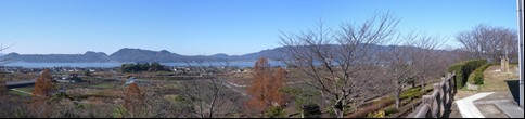 田畑が広がり茶色の葉をつけた木や冬枯れの木などが立つ大塚山公園からの眺望写真