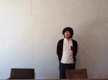 腕を後ろで組み、左方向を見ている塩田大成さんの写真