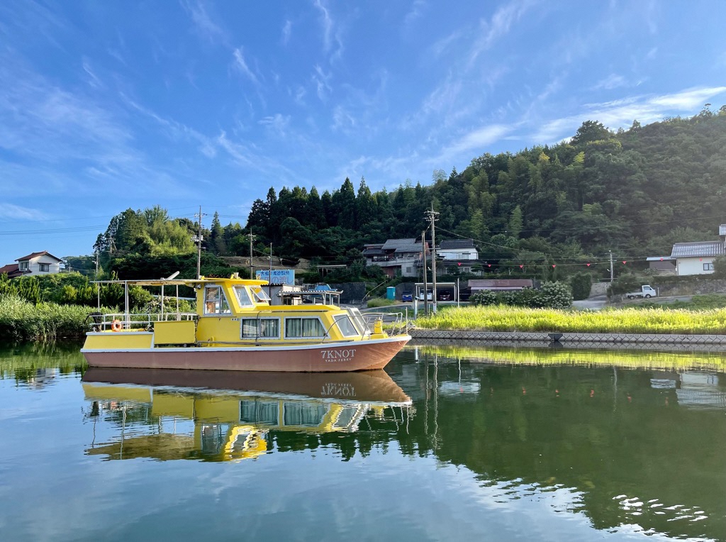 船着き場の川の上に黄色の船体の矢田の渡し船が浮いている写真