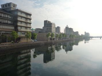 大橋川北岸沿いに大きなビルなどの建物が立ち並んでいる写真