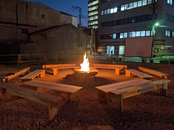 焚火を囲んで木製の長椅子を2列に六角形に設置した写真